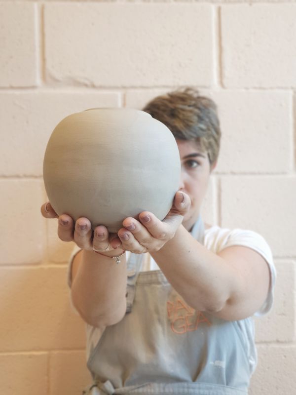 A ceramicist holds a hand-thrown clay sphere